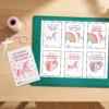 DIY valentine crafting station showing printed unicorn valentine PDF sheet on cutting mat with scissors and twine.