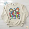 Coquette style autism awareness bow design printed on a cream-colored oversized crewneck sweatshirt with pearl accessories.