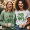 Two smiling friends wearing matching coquette shamrock designs on sage green and white sweatshirts.