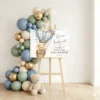 Large baby shower welcome sign displayed on easel surrounded by luxury blue and gold balloon arch decoration.