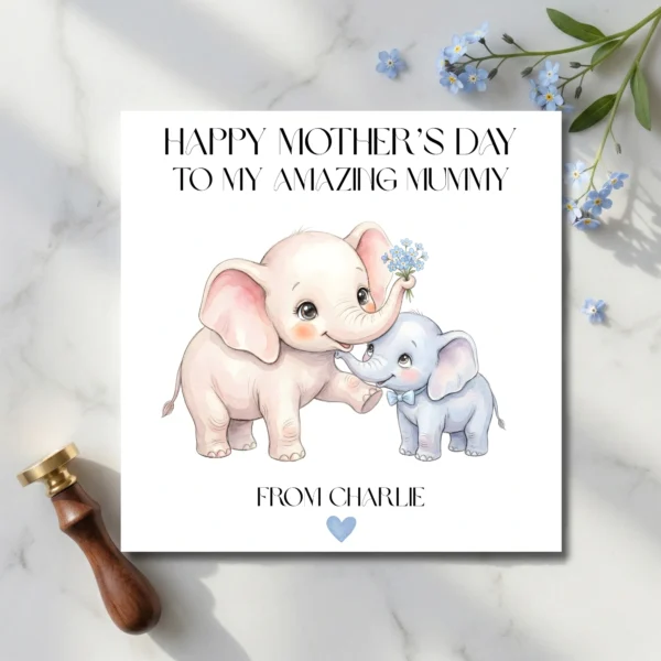 Printed square Mother's Day card with watercolor elephants lying on a marble surface next to a brass wax seal and blue forget-me-not flowers.