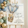 We Can Bearly Wait welcome sign on wooden easel with blue and sage green balloon garland for boy baby shower.