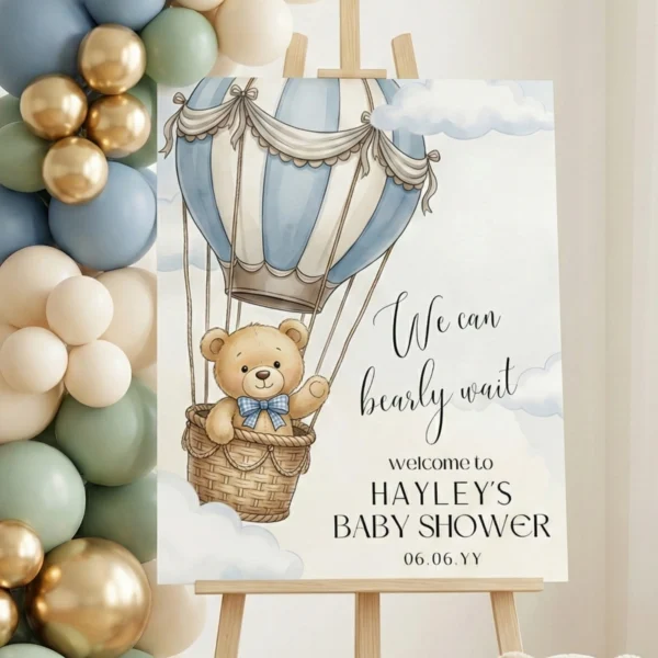 We Can Bearly Wait welcome sign on wooden easel with blue and sage green balloon garland for boy baby shower.